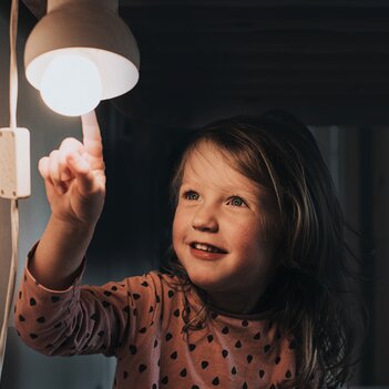 Kleines Kind zeigt freudig auf eine brennende Glühlampe. | © Getty Images