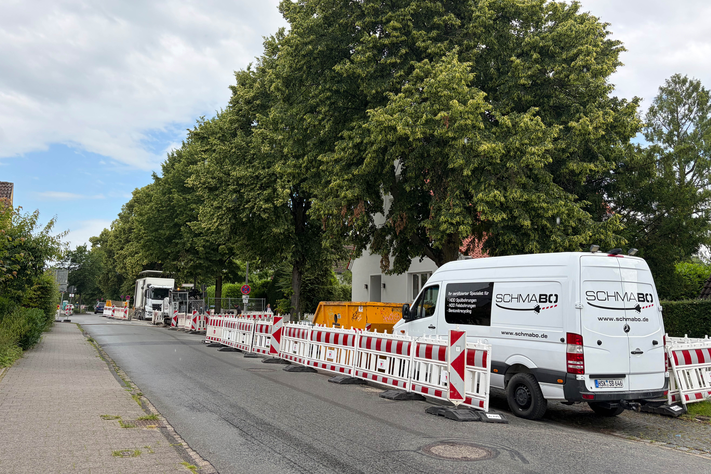Ein Foto der Schmeddingstraße: Auf dem am rechten Straßenrand sind Absperrungen, ein Container und Baufahrzeuge zu sehen. 
