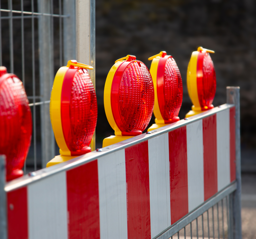 Nahaufnahme einer rotweißen Absperrschranke mit roten Signalleuchten obendrauf. | © iStock