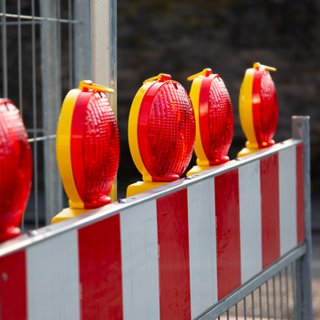 Nahaufnahme einer rotweißen Absperrschranke mit roten Signalleuchten obendrauf. | © iStock