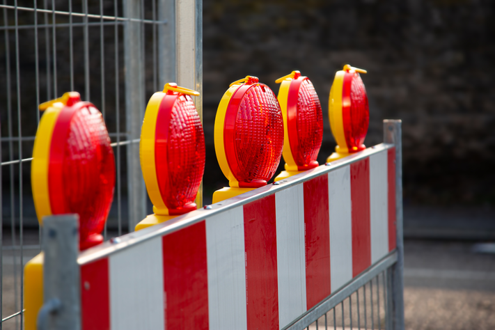 Nahaufnahme einer rotweißen Absperrschranke mit roten Signalleuchten obendrauf. | © iStock