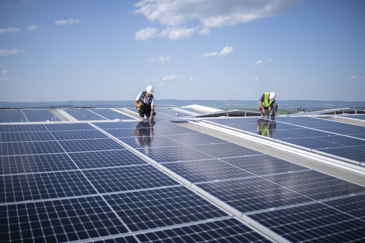 Ein Ingenieur in Arbeitsschutzkleidung bei der Wartung von Solarmodulen mit digitalem Tablet auf einer Photovoltaik-Aufdachanlage. | © Getty Images