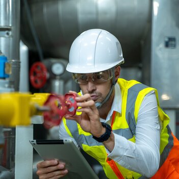 Ein Elektroingenieur, der die technischen Daten der Heizungsanlage und des Luftkompressorsystems in der Produktionsstätte überprüft. | © Adobe Stock